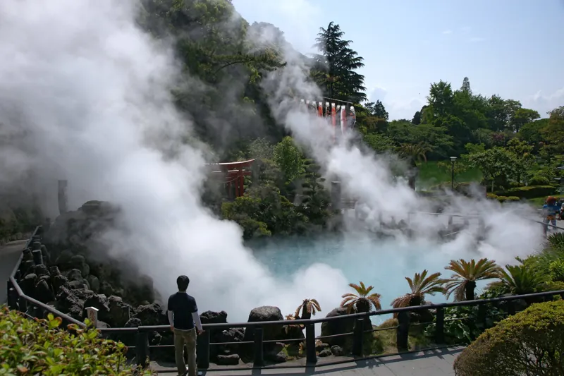 La vasca turchese di Umi Jigoku tra le colonne di vapore, con un torii rosso.