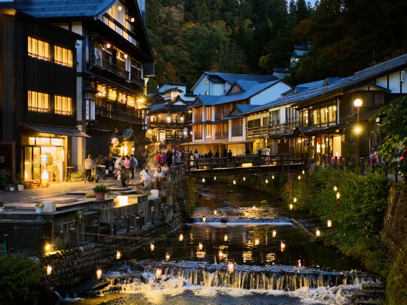 Ginzan Onsen al crepuscolo, con i ryokan in legno illuminati lungo il torrente.